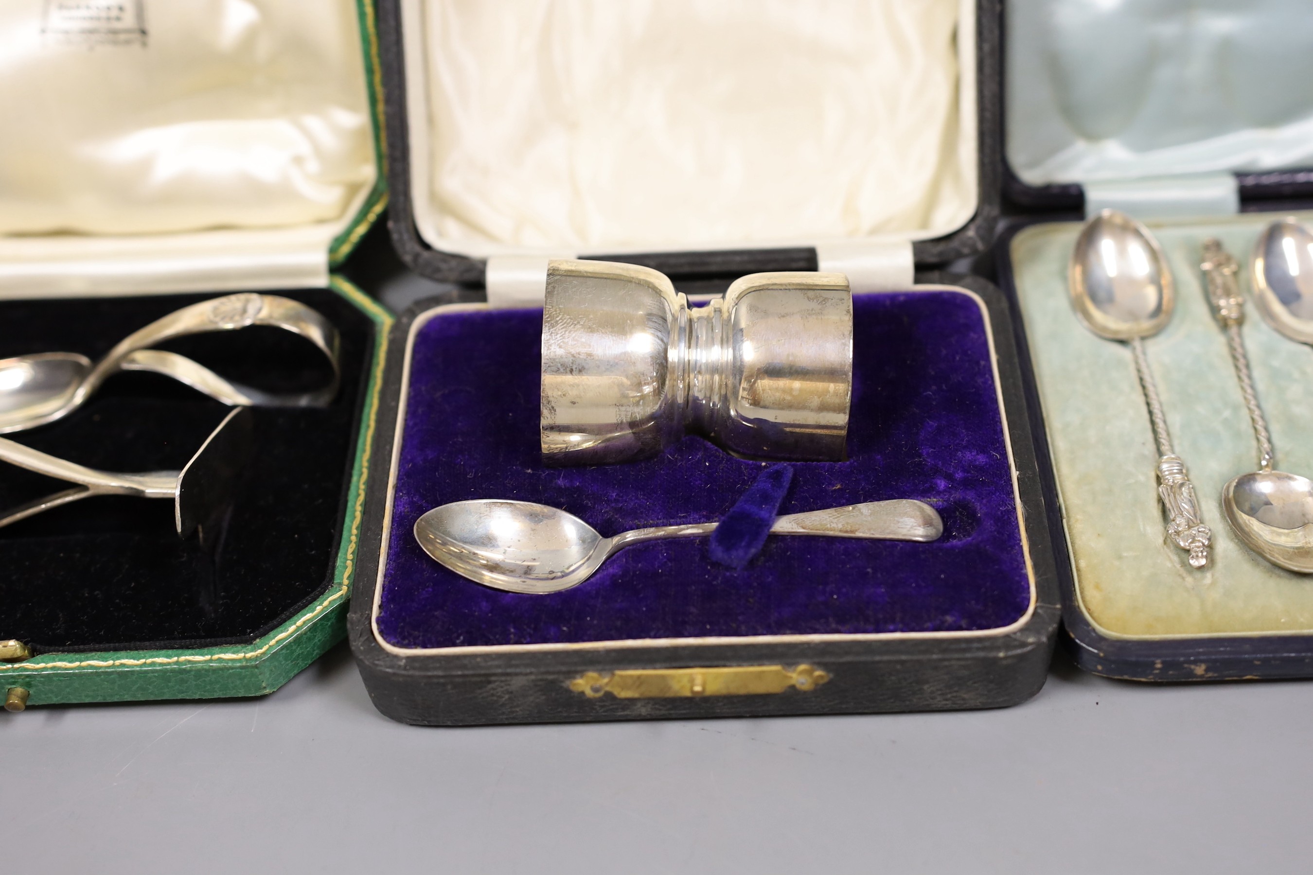 Two cased silver Christening sets, egg cup and spoon and pusher and spoon, a cased set of acanthus terminal coffee spoons, and a cased set of six apostle teaspoons and tongs, 7oz.